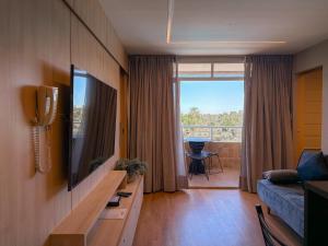 a living room with a couch and a television and a balcony at Apto Luxo Gran Lençóis Atins 503 in Barreirinhas