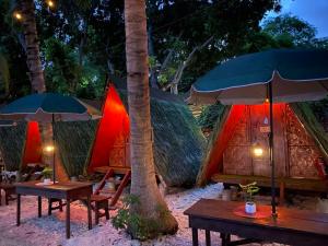 Alfonsa Tent Ground - Camp By The Sea في أوسلوب: مجموعة من الخيام مع طاولات ومظلات