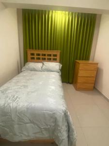 La casa de Betty في وانكايو: غرفة نوم بسرير وستارة خضراء