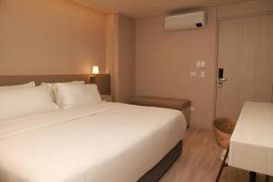 een hotelkamer met een groot wit bed en een tafel bij VPV Suites & Casino in Medellín