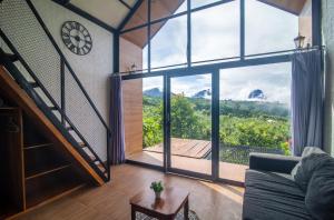 a living room with a large window and a clock at Alam Munduk Cabin in Munduk