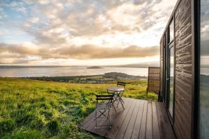 a deck with two chairs and a table on a house at Aorangi Peak Cabins 7 by Tiny Away in Rotorua