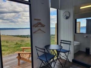a table and chairs on a porch with a view of the water at Aorangi Peak Cabins 7 by Tiny Away in Rotorua +43 photos