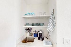 a kitchen counter with a sink and dishes on shelves at Palm Beach Condo 5 Mins to Beach Heated Pool in Palm Beach