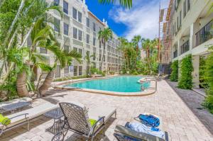 a swimming pool in a courtyard with chairs and palm trees at Palm Beach Condo 5 Mins to Beach Heated Pool in Palm Beach
