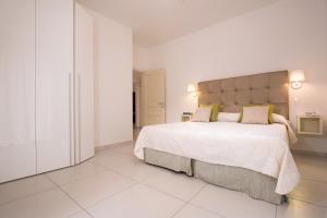 a white bedroom with a large bed with green pillows at Al Corso Apartments by AMALFIVACATION in Minori