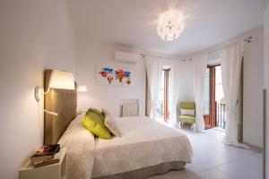 a white bedroom with a bed and a chandelier at Al Corso Apartments by AMALFIVACATION in Minori