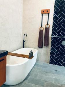 ウブドにあるDewangga Suiteの白い浴槽とシャワーとバスタブを備えたバスルーム