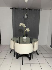 Un comedor con una mesa de cristal y sillas blancas. en Sweet Home, en San Juan