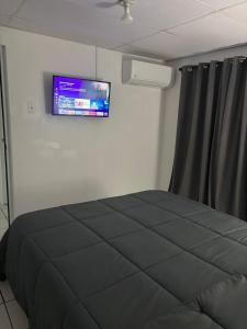 Un dormitorio con una cama y un televisor en la pared. en Sweet Home, en San Juan
