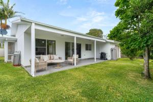 a white house with a patio and a yard at The Little Husky by Experience Jervis Bay in Huskisson