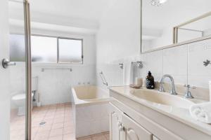 a white bathroom with a sink and a tub at The Little Husky by Experience Jervis Bay in Huskisson +11 photos