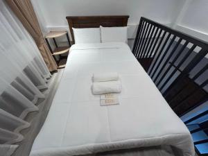 two beds in a room with white sheets and towels at Tim's Guest House in Butuan +20 photos
