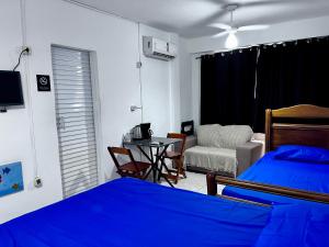 a bedroom with a bed and a table and a chair at Kit do ALEX - AVIAÇÃO - a uma esquina da praia - Ar Condicionado in Praia Grande