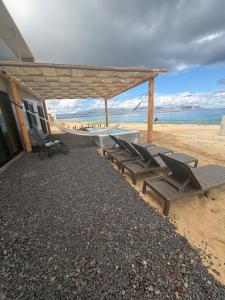 Un grupo de tumbonas debajo de un pabellón en la playa. en Oceanfront Private Pool Villa Luxury Open-Concept Retreat, en La Paz