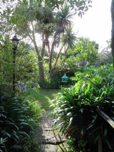 um jardim com um caminho e uma casa de pássaros em Merrybrook Studio em Oamaru