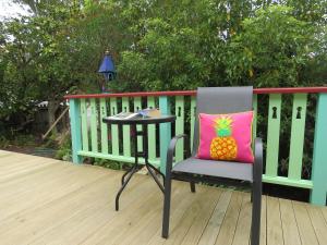 una silla con almohada de piña y una mesa en la cubierta en Merrybrook Studio en Oamaru