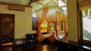 a bedroom with a canopy bed with orange pillows at Nomadic Resort Bali in Canggu