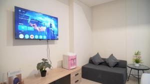 ジャカルタにあるSpacious and Homey Studio at Cleon Park Apartment By Travelioの壁に薄型テレビが取り付けられたリビングルーム