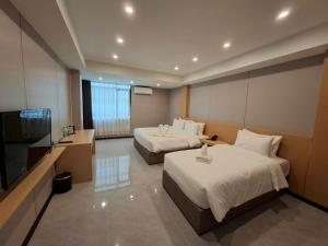 een hotelkamer met twee bedden en een flatscreen-tv bij Velin Pattaya Hotel in Ban Nong Chaeng