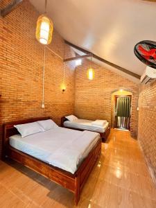 a bedroom with two beds and a brick wall at Nam Cat Tien Retreat in Tân Phú +26 photos