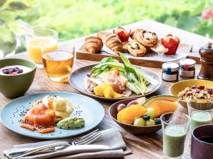 Una mesa de madera cubierta con platos de comida y bebidas. en Grand Mercure Awaji Island Resort & Spa, en Minamiawaji