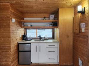 een keuken in een tiny house met een wastafel en een raam bij Chalet Beausite in Saint-Philémon