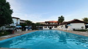 Duplex com Hidro em Condomínio Luxo com 3 Praias في انغرا دوس ريس: حمام سباحة كبير مع كراسي ومظلات