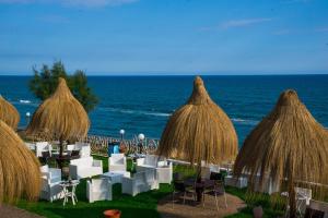 a group of tables and chairs with umbrellas and the ocean at Holiday Village in Fondi