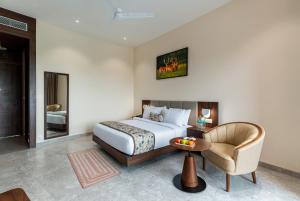 Osian Valley Resort & Spa Kumbhalgarh في Jāmb: غرفة نوم بها سرير وكرسي وطاولة +14 صورة