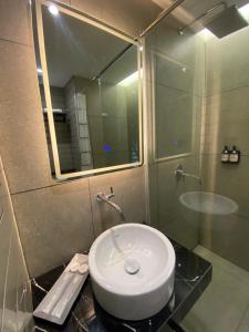 Un baño con lavabo y ducha con espejo. en MBS HOTEL Medan, en Medan