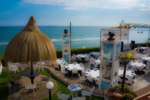 a restaurant with white tables and chairs and the ocean at Holiday Village in Fondi