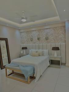 a white bedroom with a large bed and two tables at Las Olas Apartment, Juan Dolio in Guayacanes +7 photos