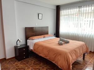 ein Schlafzimmer mit einem Bett mit einer orangefarbenen Decke und einem Fenster in der Unterkunft Cozy & Centric Apartment in great location! in Cusco