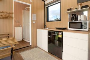Black Horse Cabin 3 by Tiny Away في Waitoki: مطبخ مع ميكروويف وموقد