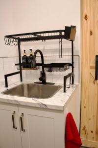 a kitchen sink with a metal shelf above it at Studio - Cozy Downtown Hideaway in Sudbury
