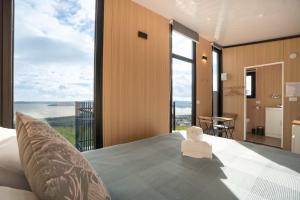 a bedroom with a bed with a view of the ocean at Black Horse Cabin 4 by Tiny Away in Waitoki