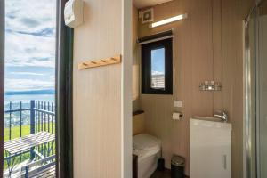 a bathroom with a toilet and a balcony at Black Horse Cabin 4 by Tiny Away in Waitoki +37 photos