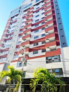 een hoog gebouw met palmbomen ervoor bij Apartamento Elegante 2 Quartos in Balneário Camboriú