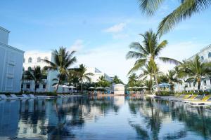 a pool at a resort with palm trees and buildings at HADU Hotel & Café Phu Quoc in Phú Quốc
