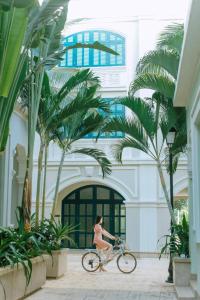 a woman riding a bike in front of a building at HADU Hotel & Café Phu Quoc in Phú Quốc