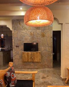 Vota Ranch Luxury Villa Stay & Nature Retreat في Machakos: ثريا كبيرة في غرفة معيشة ذات جدار حجري