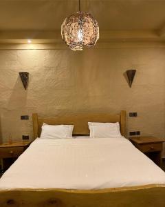 Vota Ranch Luxury Villa Stay & Nature Retreat في Machakos: غرفة نوم بسرير ابيض كبير مع ثريا