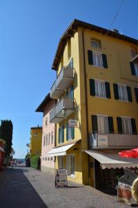 a yellow building with balconies on a street at Stella Sport Apartments in Nago-Torbole