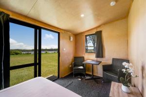 a room with a bed and a desk and a window at Waitangi Holiday Park in Paihia +39 photos