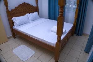 a bedroom with a bed with a wooden frame at Alpha Homes in Mombasa