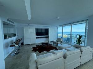 a living room with a white couch and a television at Beachfront two story apartment in Miami Beach