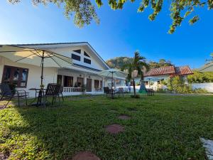 Three CoCo Villa AoNang Beach في Ao Nang : منزل فيه كراسي ومظلات في ساحة