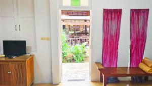 Baan Toom Village and Resort في تشانتابوري: غرفة بها باب وستائر حمراء وطاولة