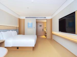 een hotelkamer met een groot bed en een flatscreen-tv bij JI Hotel Suzhou Dushu Lake Ecological Park in Suzhou